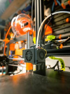 Close-up of a 3D printer in a workshop with visible tools and spool.