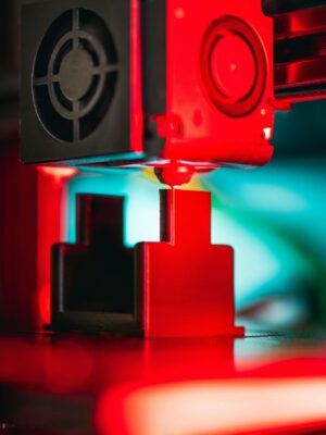 Vibrant image of a 3D printer working on a design with red lighting.